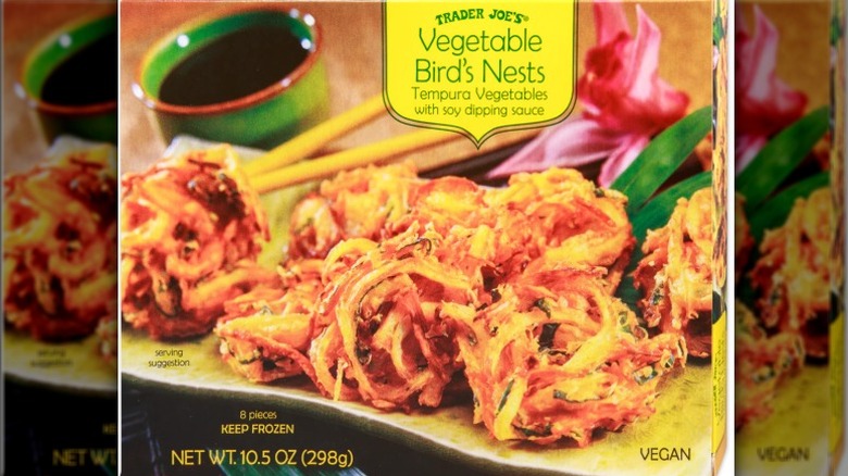 A beauty shot of Trader Joe's vegetable bird's nests box with fried nests, soy sauce, chopsticks and a flower on the cover.