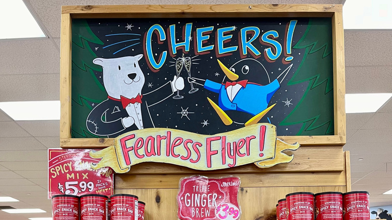 A Trader Joe's store display featuring a Cheers sign with a bear and penguin toasting with champagne glasses