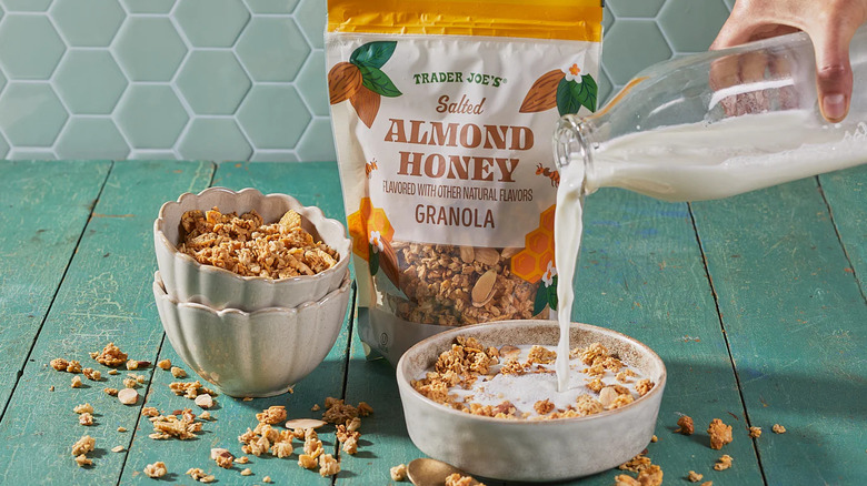 A hand pours milk into a bowl of Traer Joe's Salted Almond Honey Granola