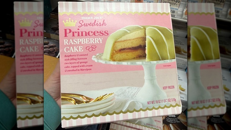 A person holding a box of Trader Joe's Swedish Princess Raspberry Cake