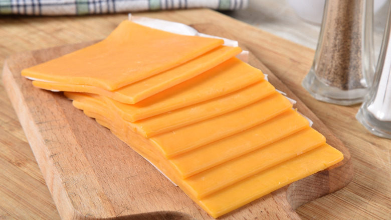 Thick slices of cheddar cheese on a wooden cutting board