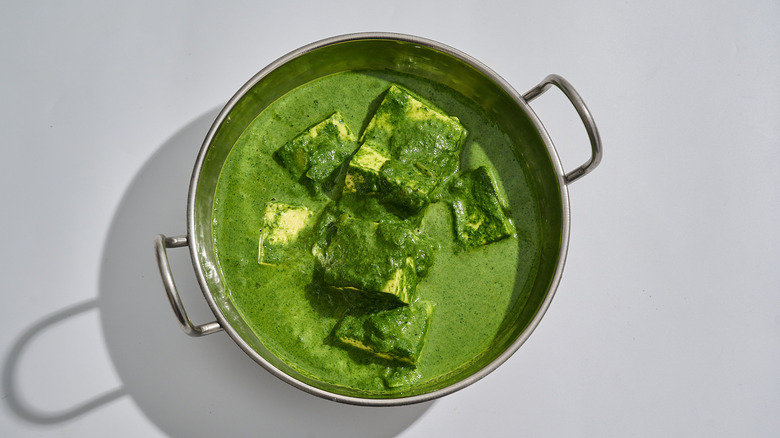 A bowl of palak paneer is on a table
