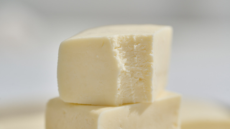 Pieces of paneer are stacked on top of each other and one has a bite taken out of it