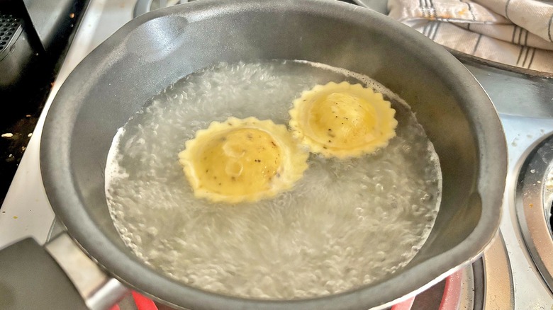 Two ravioli boiling in small pot of water