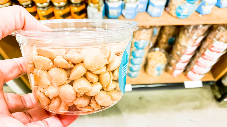 person holding container of nuts in front of Trader Joe's products in containers