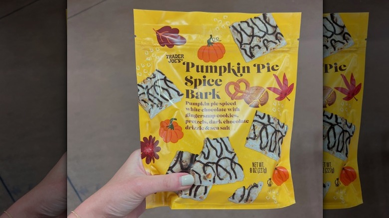 Hand holding a yellow bag of Trader Joe's Pumpkin Pie Spice white chocolate Bark
