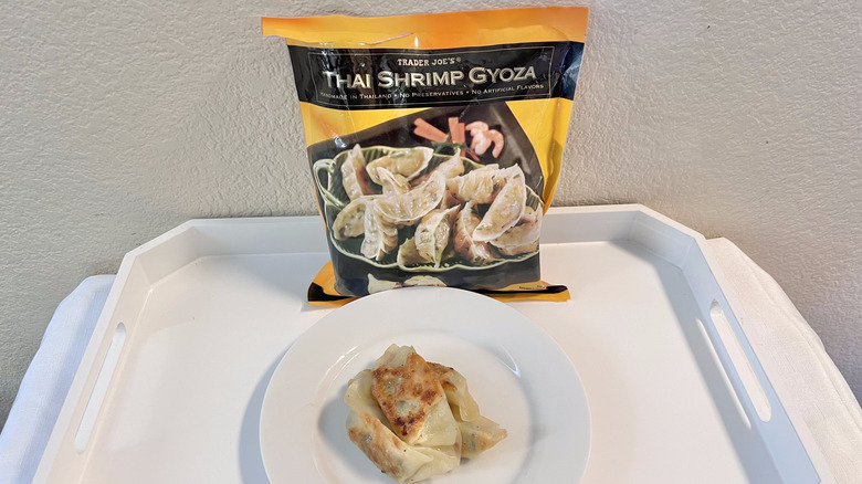 A bag of Trader Joe's Thai Shrimp Gyoza with some cooked gyoza served on a plate