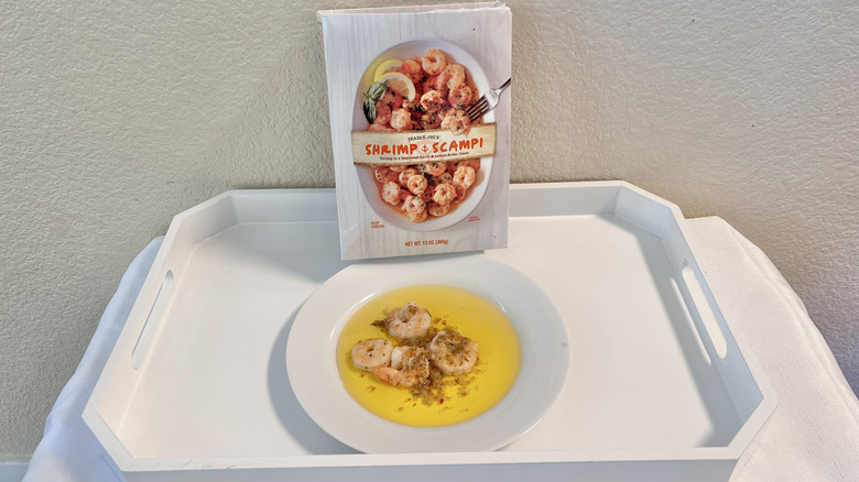 A pack of Trader Joe's shrimp scampi with some scampi cooked and served on a plate
