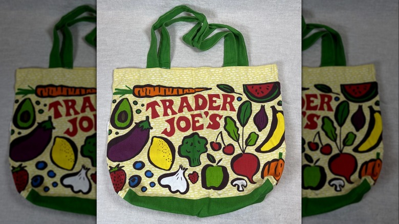 Yellow and green Trader Joe's tote bag with fruit and vegetable illustrations and company logo