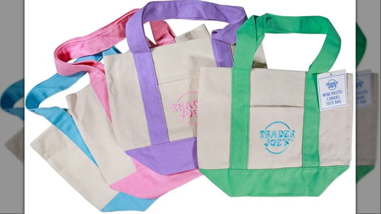 Trader Joe's mini canvas tote bags in pink, purple, blue, and green arranged in row
