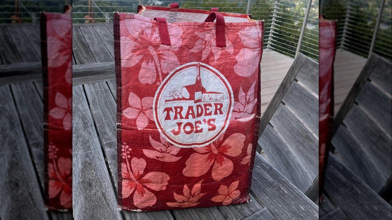 Red and pink plastic Trader Joe's reusable bag with hibiscus and plumeria pattern