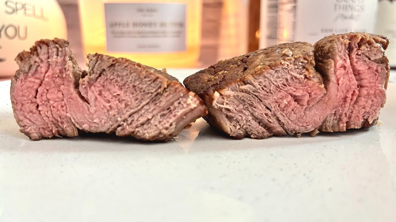 Trader Joe's filet mignon cut in half, cooked medium on a white plate