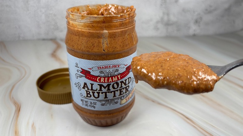 Open jar of Trader Joe's almond butter next to a spoonful of almond butter