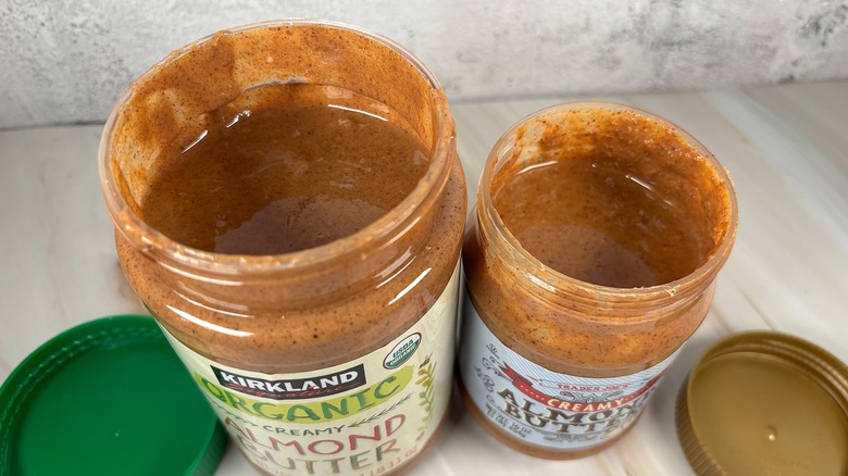 Side-by-side jars of Kirkland and Trader Joe's almond butters with the lids off