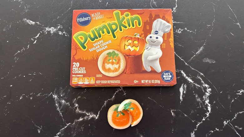 Pillsbury pumpkin shape sugar cookie dough package above sugar cookies on countertop