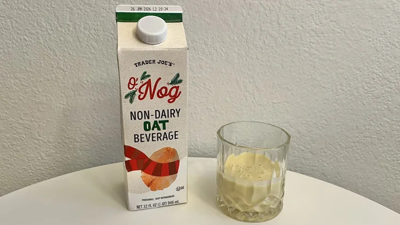 A container of Trader Joe's O'Nog beside a glass of the drink