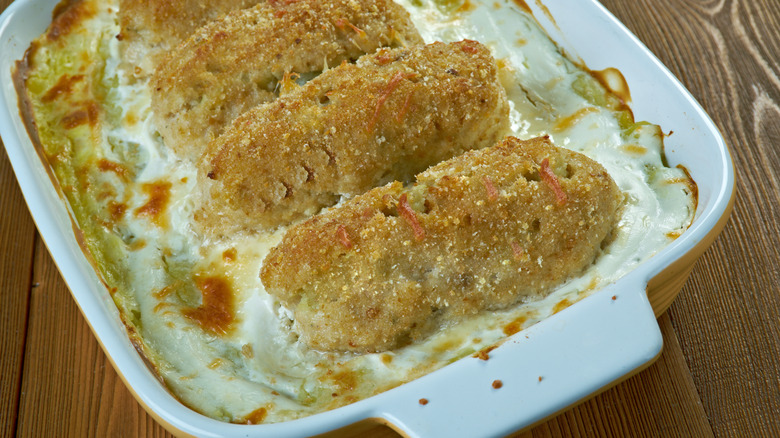 A fish stick potato casserole with a crispy Brown top in a white casserole dish on a wooden table