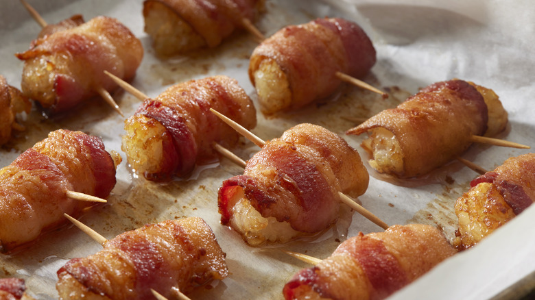 bacon wrapped tater tots on a baking sheet