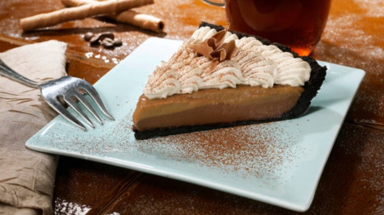 Slice of chocolate cream pie with chocolate cookie crust, whipped cream, and chocolate shavings
