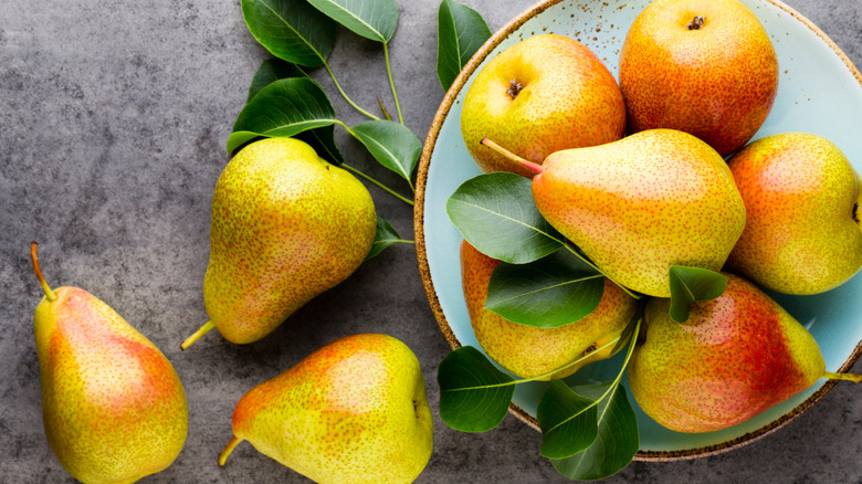 Top view of a pear arrangement alongside green leaves.