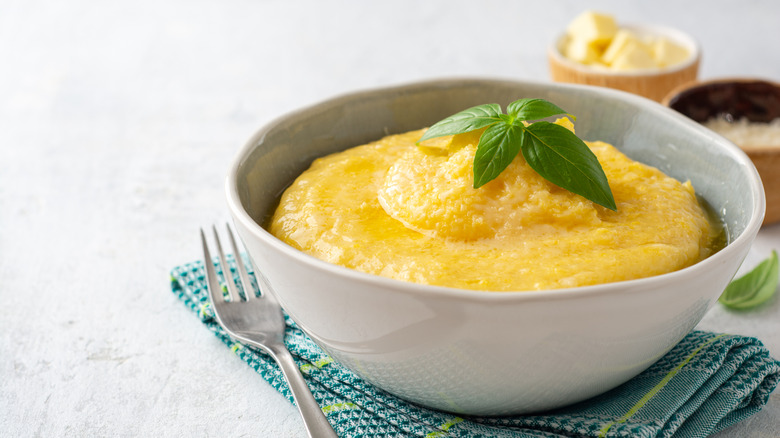 A bowl of polenta with a sprig of basil on top