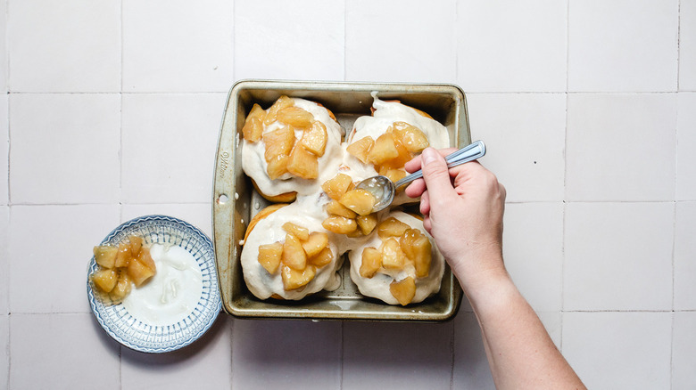 Topping cinnamon buns with apple pieces