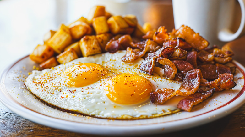 A plate of bacon, eggs, and home fries at a diner.