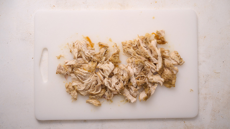 shredding chicken on a cutting board