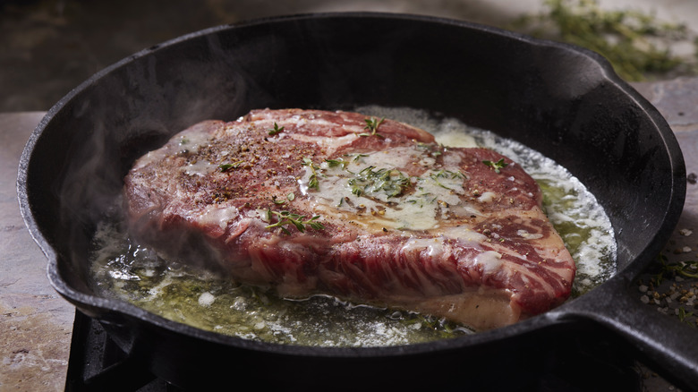 ribeye steak searing in pan