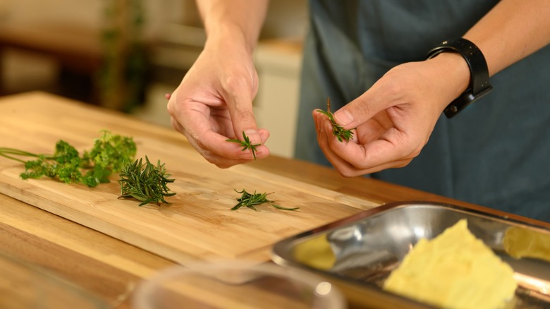 Hands cutting up fresh herbs to make compound butter