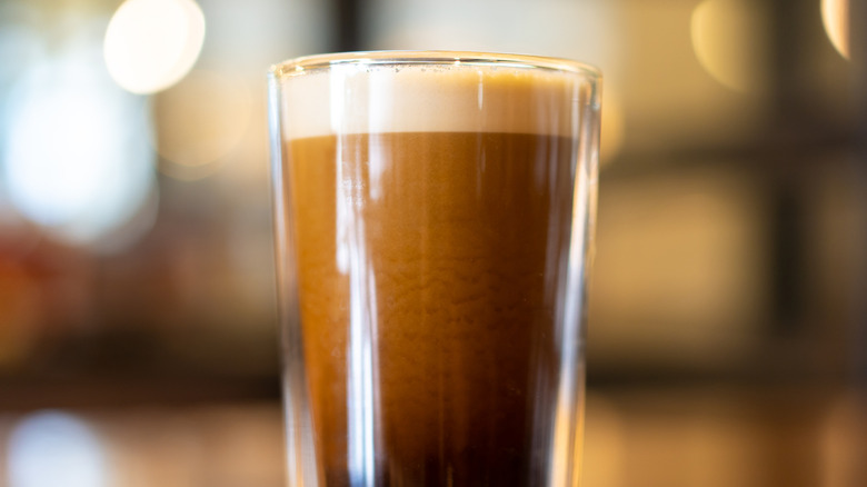 Iced coffee in glass with layer of pale foam on top