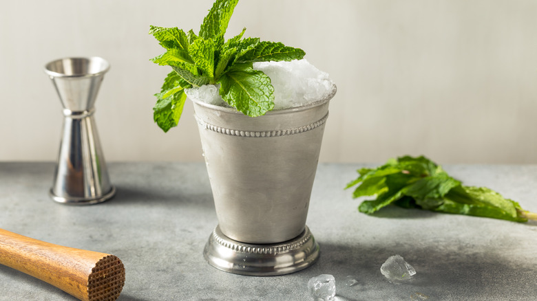 classic mint julep in a metal cup with metal shot glass, muddler, and fresh mint