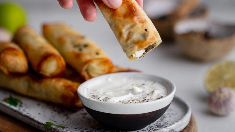 hand dipping spinach dip roll