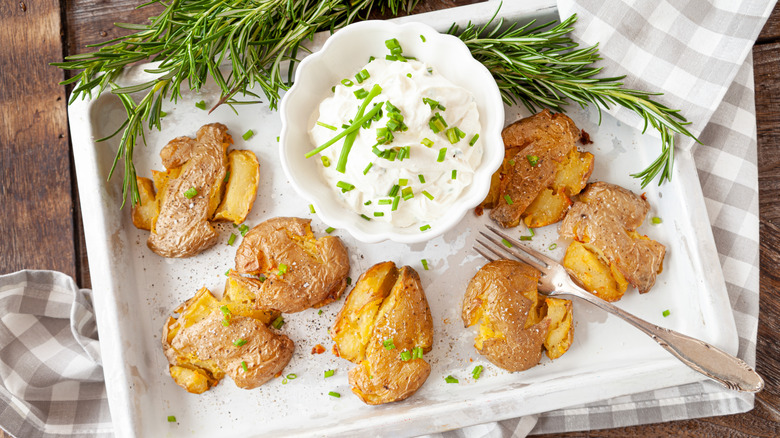 smashed potatoes on white tray with garlic sauce