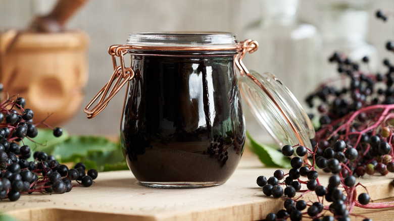 A jar of homemade syrup surrounded by fresh berries
