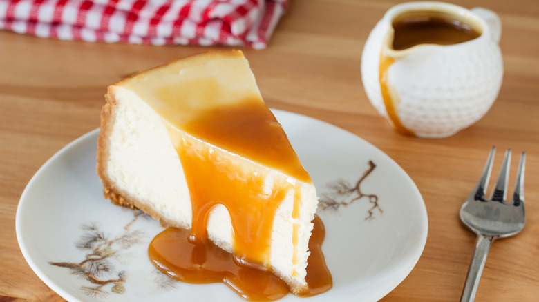 A slice of cheesecake topped with caramel sauce on a table