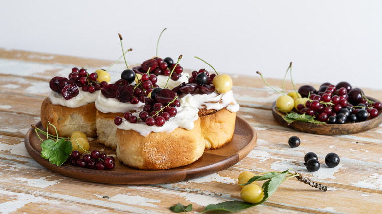 A plate of sweet bread rolls topped with cream and berries