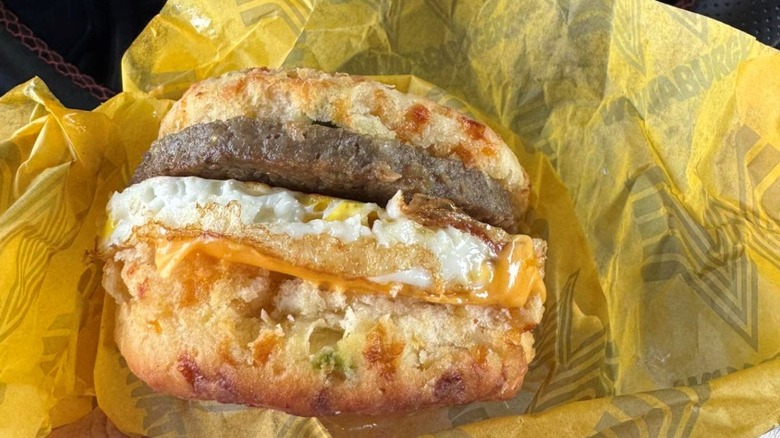 person holding a Whataburger breakfast sandwich with a jalapeño cheddar biscuit