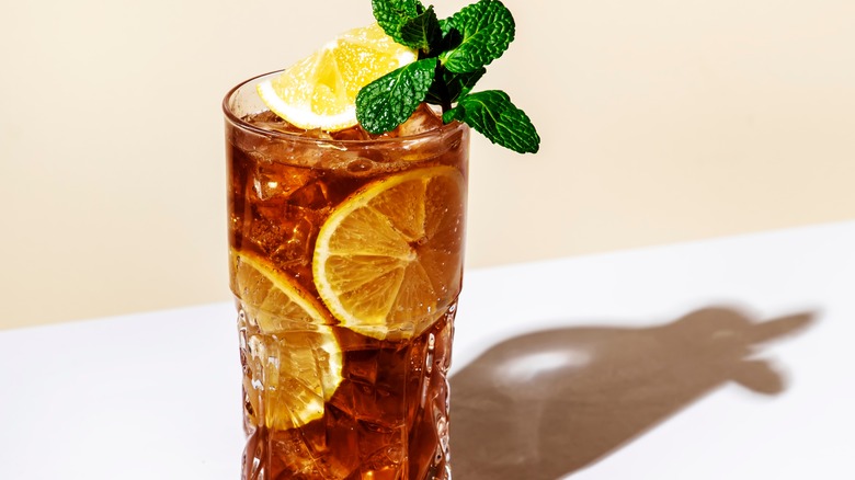 Closeup of a glass of iced tea garnished with mint and lemon slices