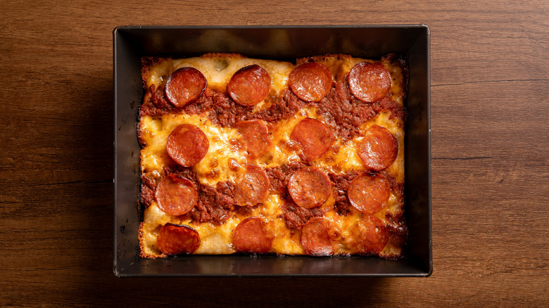 Detroit style pizza in a pan on wood