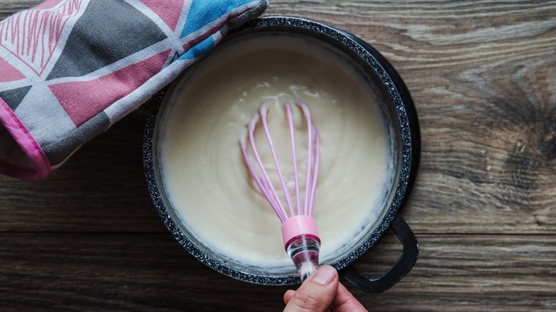 Top-down view of béchamel sauce being whisked in a pot