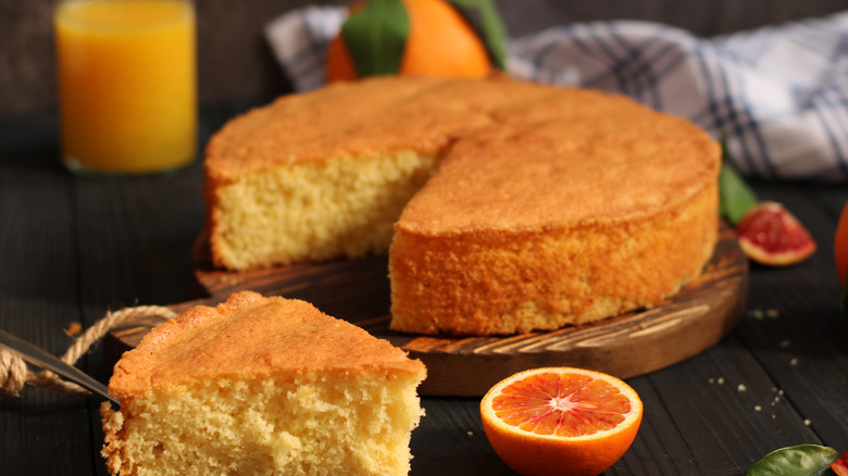 A slice of orange cake next to a halved orange