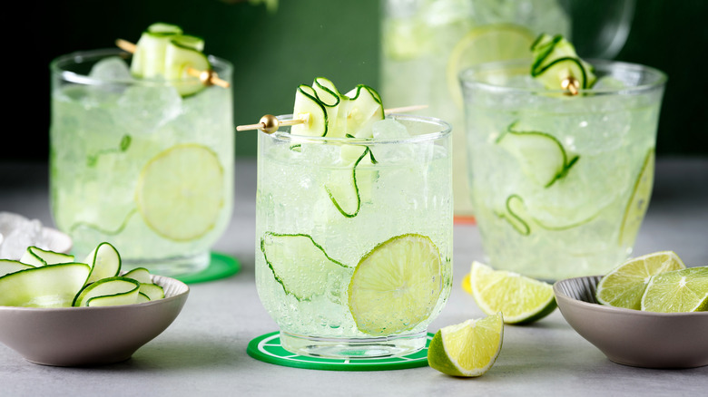Vodka tonic cocktails in small decorative glasses, garnished with lime and cucumber ribbons