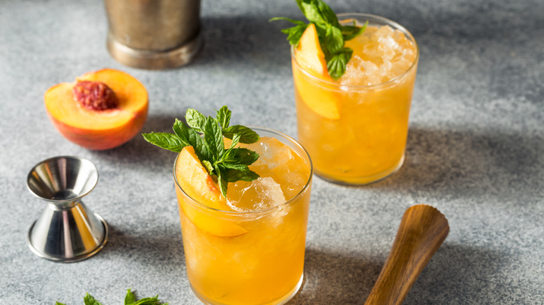 Two Hairy Navel cocktails garnished with fresh mint leaves and slices of peach
