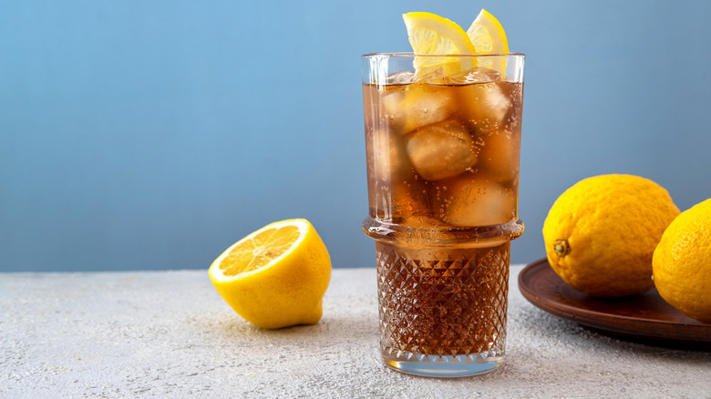 A highball glass containing iced tea and vodka garnished with lemon slices