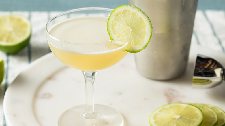 A couple glass containing a vodka gimlet garnished with a lime wheel