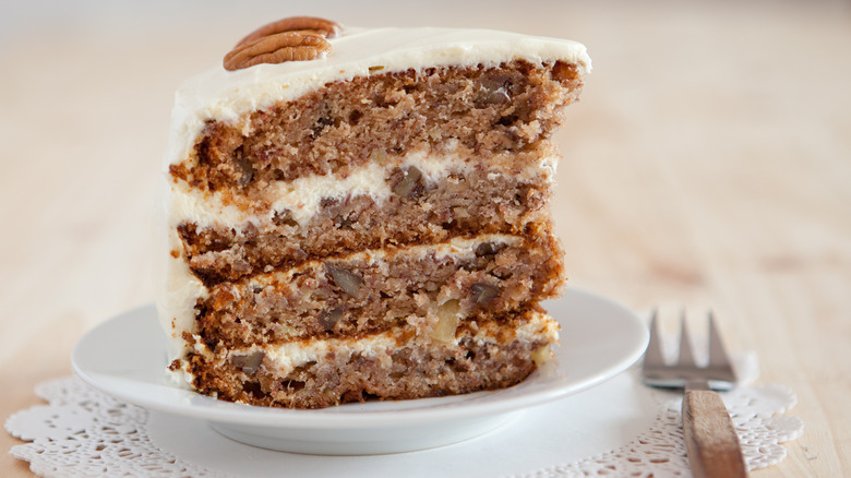 Hummingbird cake slice on a white plate with a fork