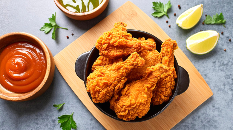 Plated fried chicken and ketchup on a wooden cutting board