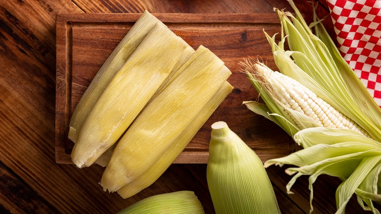 Corn and husks on cutting board