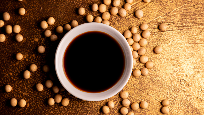 Dipping bowl of soy sauce with soybeans around it